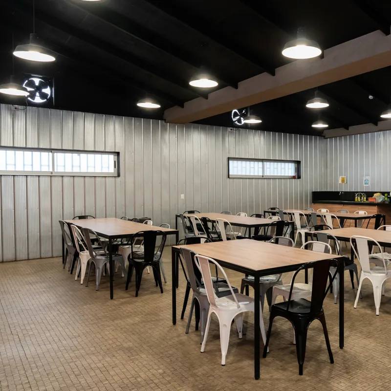 Comedor comercial con mesas, sillas metalicas, cielo negro y revestimientos metalicos