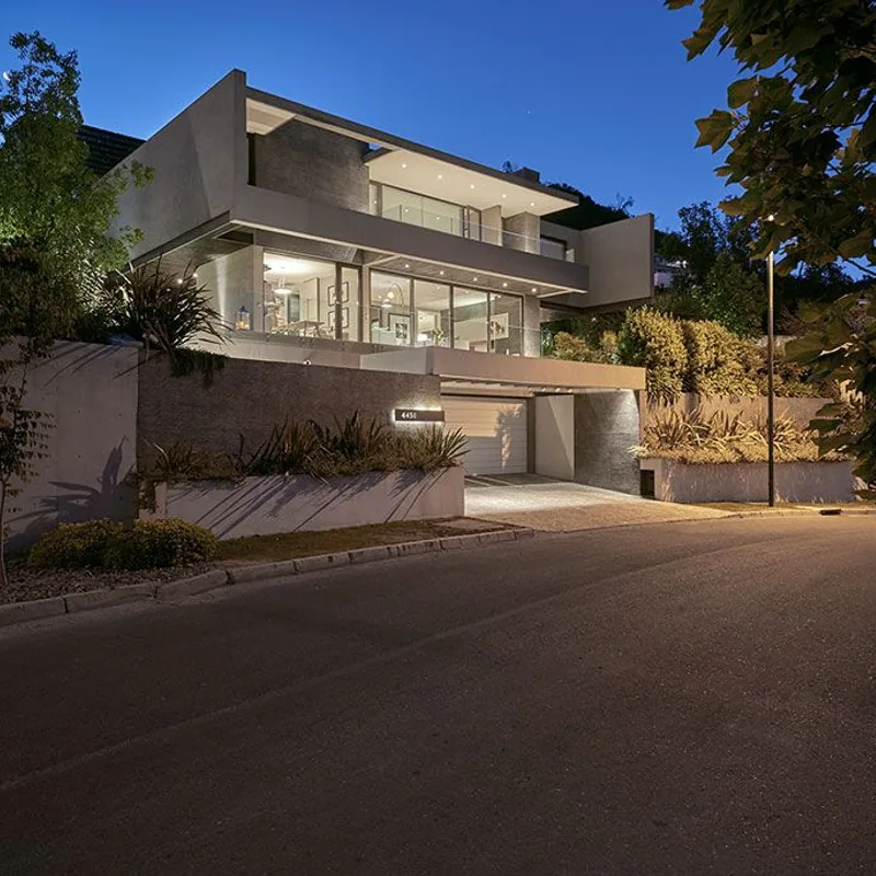 Fachada nocturna de vivienda residencial con grandes ventanales e iluminacion exterior