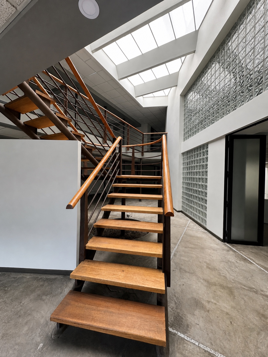 EX MOSIMO, escalera principal de madera bajo lucernarios